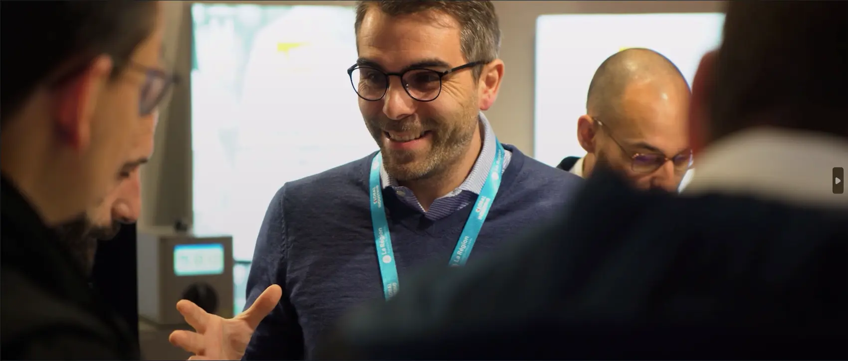 Professionnels en discussion lors d’un événement, échangeant de manière informelle autour d’un stand, dans une ambiance conviviale.