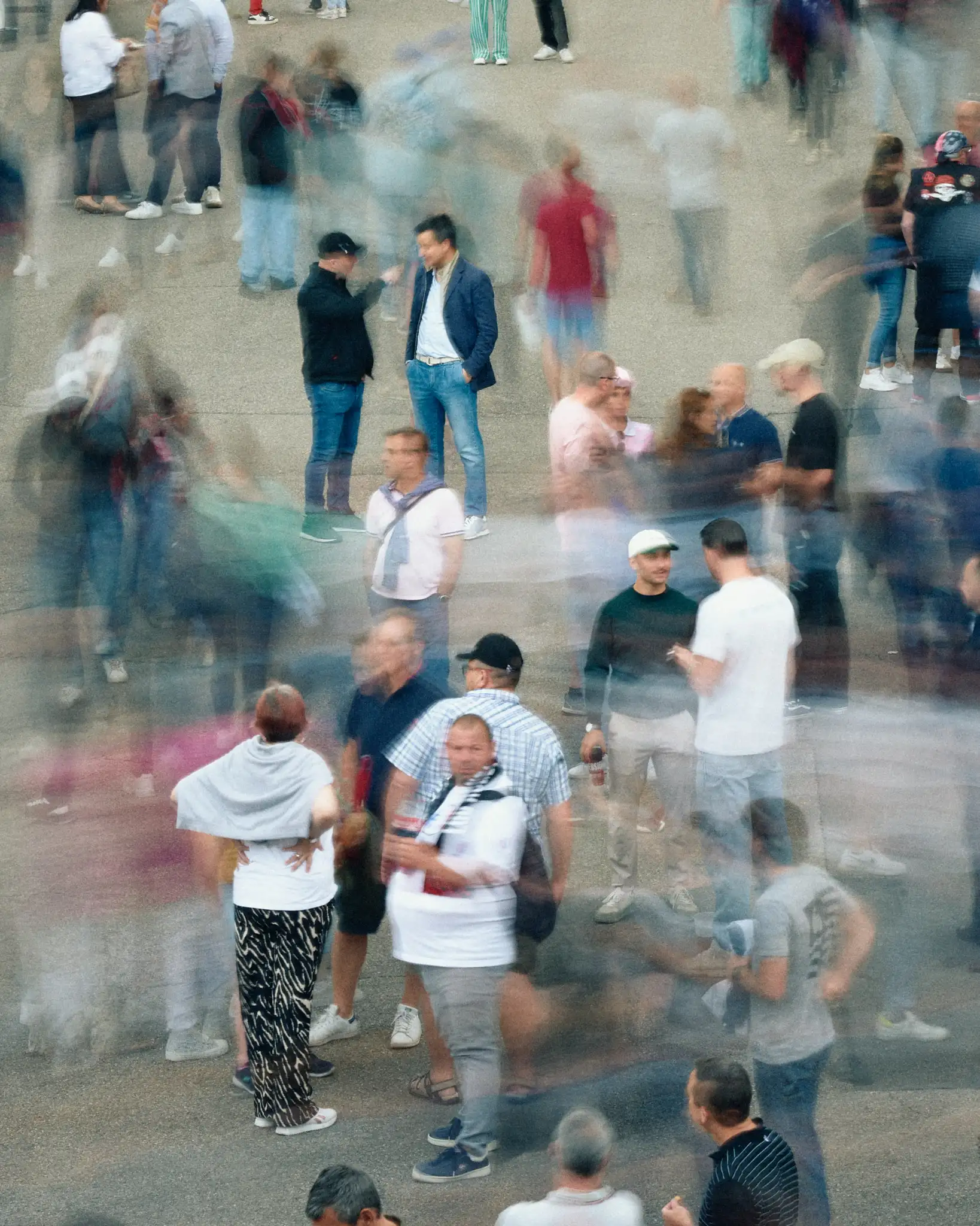 Foule de visiteurs lors d’un événement, avec des personnes en mouvement créant un effet de flou autour de quelques individus immobiles en train d’échanger.