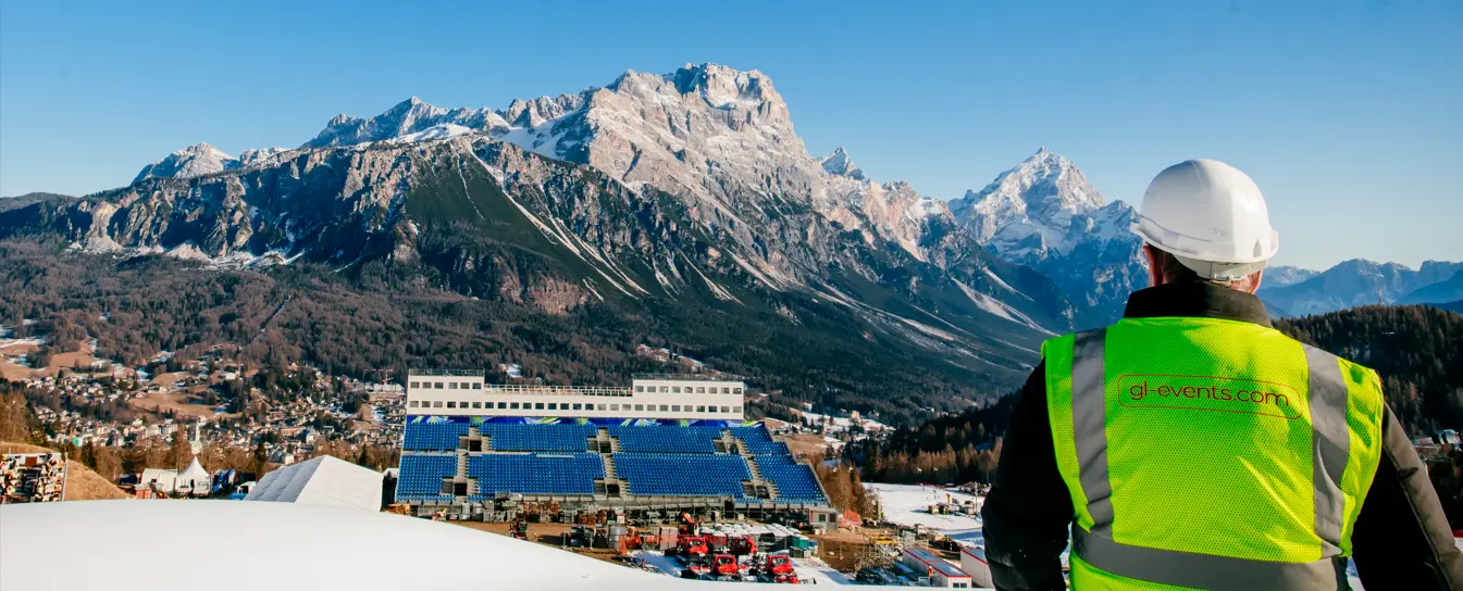 Un technicien observe un site événementiel en montagne, illustrant la préparation et la gestion d’infrastructures dans un environnement exceptionnel.