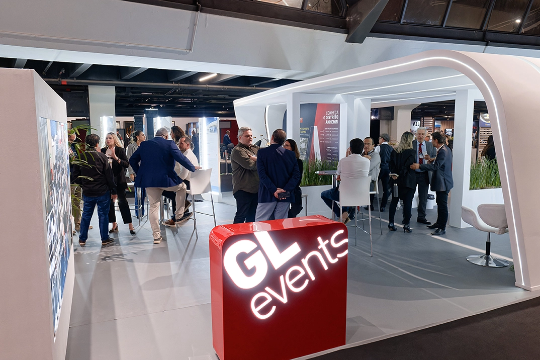 Un stand GL events accueille des visiteurs lors d’un salon professionnel, où des participants échangent dans un espace moderne et lumineux.