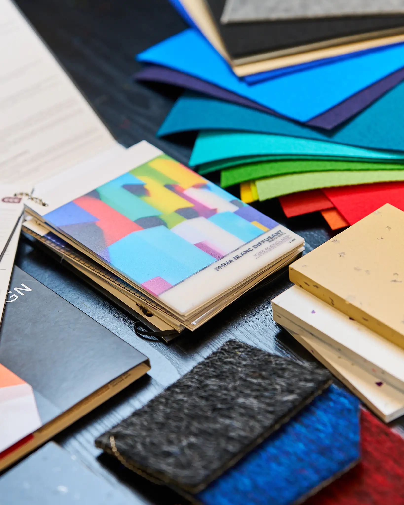Échantillons de matériaux et nuanciers colorés disposés sur une table, utilisés pour le design et la création.