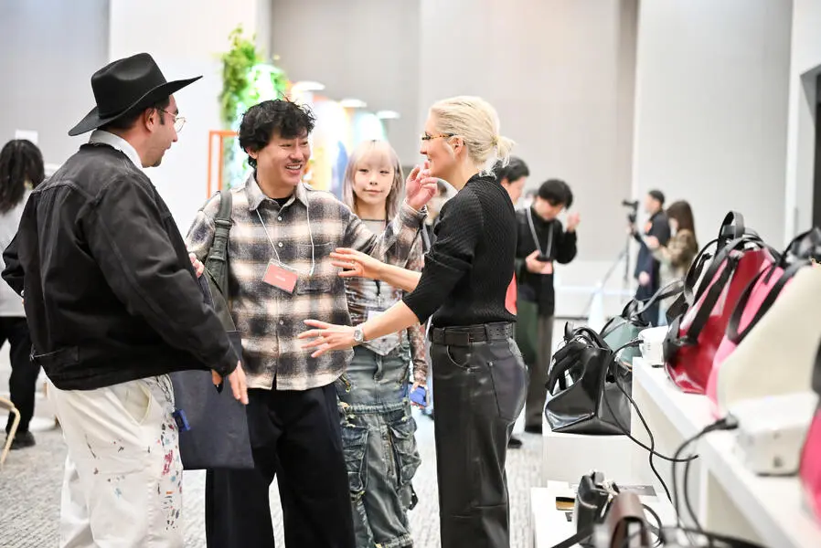 Des visiteurs échangent dans un espace d’exposition, entourés de produits présentés sur des stands, dans une ambiance conviviale.