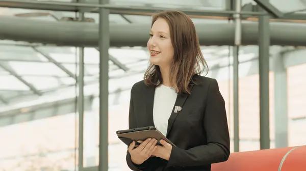 Une hôtesse d’accueil professionnelle, tablette en main, prête à orienter et accompagner les visiteurs.