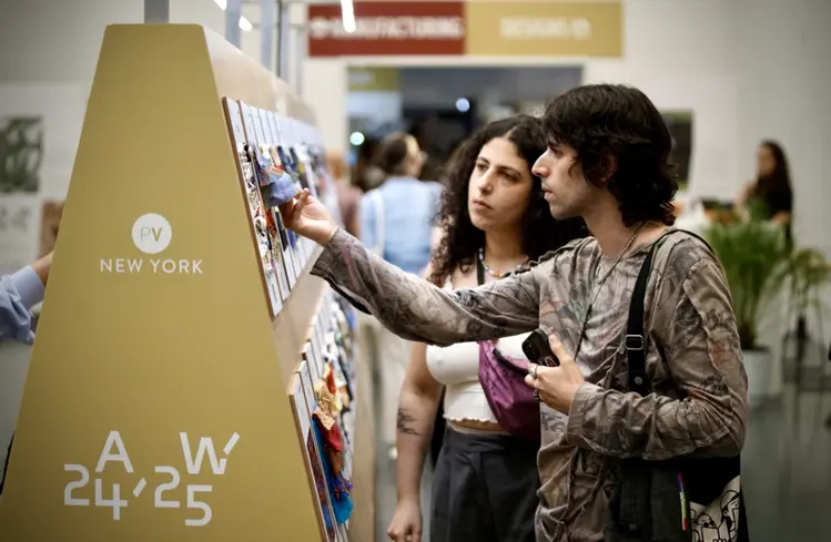Des visiteurs explorent un stand lors d’un salon professionnel, examinant des échantillons et des matières, dans un environnement propice à l’inspiration, aux échanges et à la découverte de nouvelles tendances.